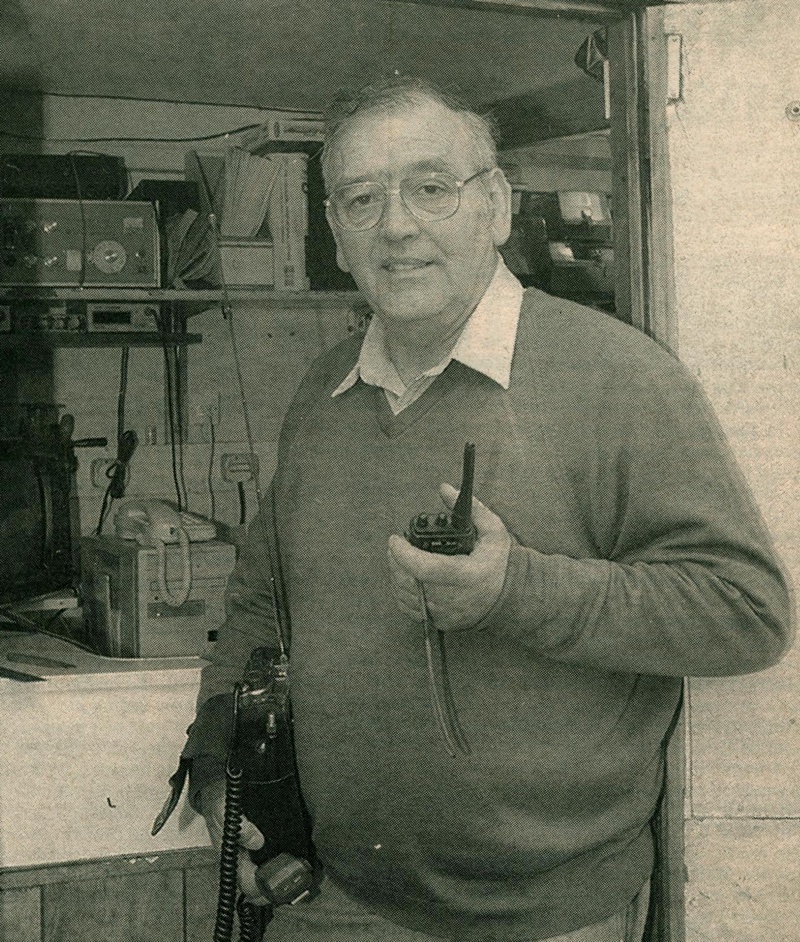 Lewis Kirby stood holding 2 radios in the doorway to his shack.